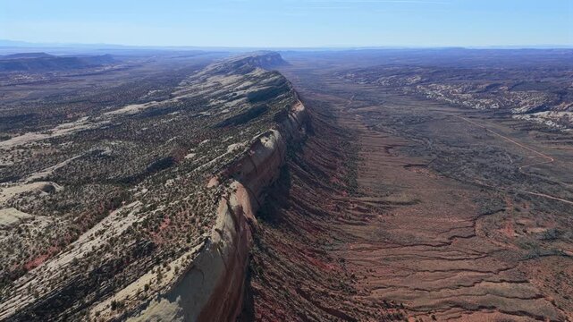 A massive hogback ridge stretches across a vast desert landscape in this high-altitude drone shot. The dramatic erosion and layered sediment create a rugged, almost alien terrain perfect for travel.