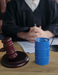 Judge sitting at a desk with a gavel and a blue barrel during a court session in a legal