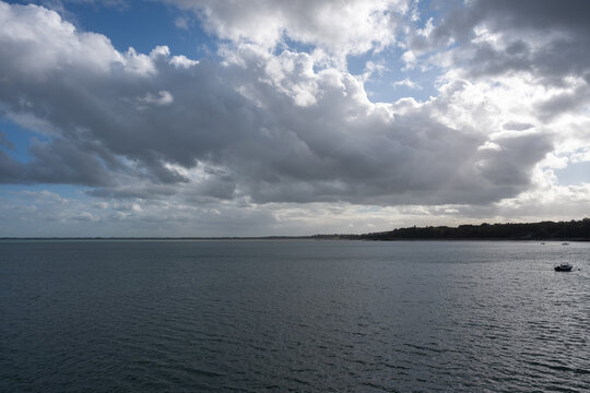 Large paysage marin sous un ciel partiellement nuageux, avec de vastes &eacute;tendues d&rsquo;eau calme et une ligne c&ocirc;ti&egrave;re visible &agrave; l&rsquo;horizon. Lumi&egrave;re naturelle cr&eacute;ant une atmosph&egrave;re paisible.
