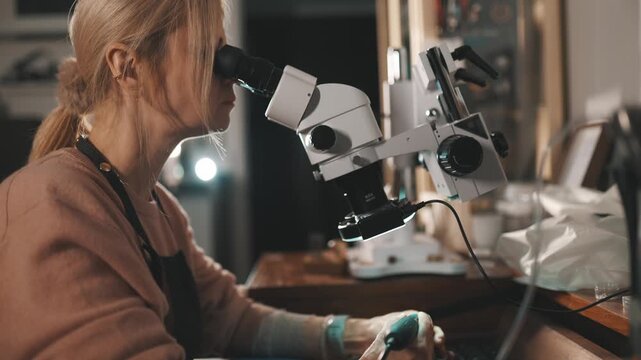 Female jeweler using a microscope for stone setting