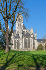 Fototapeta premium Saint Ouen Abbey Church with wide green lawn in front, architecture captured on bright spring day, architecture lines clear against blue sky, historic building shown in calm natural light