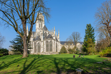 Obraz premium Saint Ouen Abbey Church in Rouen France on sunny spring day, abbey rising above fresh green grass and blue sky, abbey architecture glowing in daylight, abbey exterior surrounded by calm open space