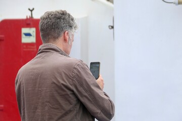 Mann fotografiert etwas mit seinem Handy auf einer F&auml;hre