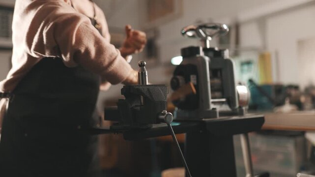 Jeweler shaping metal with hammer in workshop