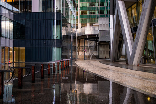 Wet plaza reflection of architecture for corporate business finance office buildings in Paris La Defense France after rain with glossy pavement and light