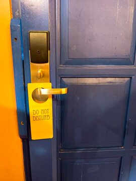 Hotel room door with electronic lock and do not disturb sign hanging on handle