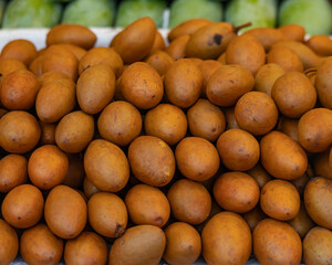 A pile of brown fruit with a few green ones in the background