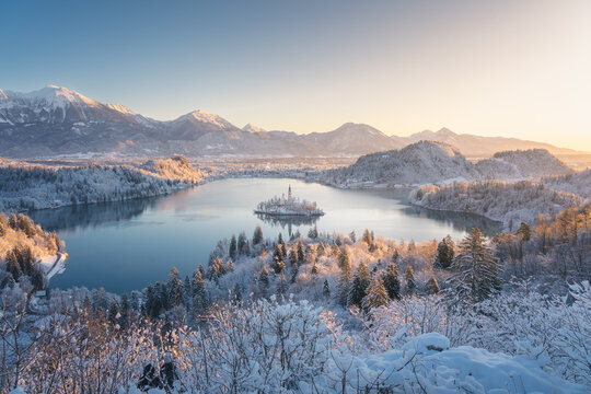 Aerial view of the snow-dusted landscape embracing the serene lake and the iconic Bled Island with its church, Bled, Radovljica, Slovenia.