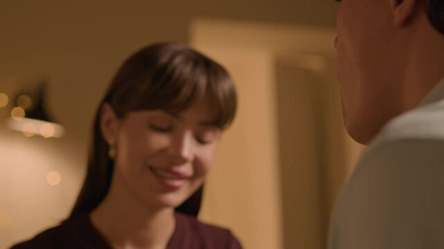 Tilt up shot of young Caucasian girlfriend giving grape to her boyfriend while drinking white wine together at home