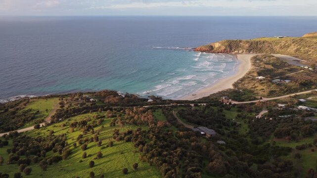 Epic sunset aerial of Snelling Beach and lush rolling green coastal hills in Kangaroo Island in South Australia a popular nature reserve and travel destination in the South Pacific.