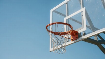 Outdoor basketball hoop with clear backboard and net against blue sky