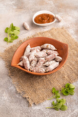 Small smoked Chicken sausages in clay bowl on brown concrete. side view, close up