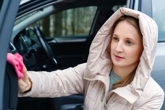 A female driver wipes the door of her car. Wet cleaning, cleanliness