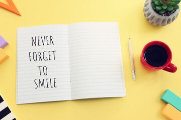 Fototapeta premium Notebook with motivational text. Never forget to smile. yellow background