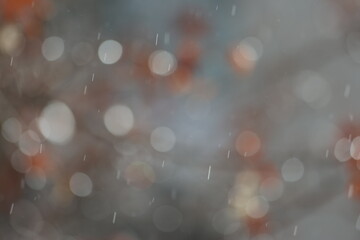 Heavy Rain Falling Against Blurred Autumn Background: Close-up of Raindrops with Bokeh Effect and Soft Orange Fall Leaves in a Moody Outdoor Scene