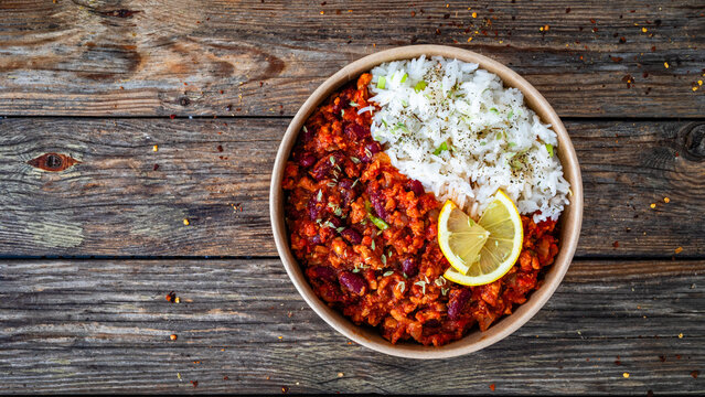 Chili con carne with rice to go on wooden table. Top view