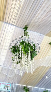 Ornate chandelier adorned with lush white wisteria and green foliage decoration