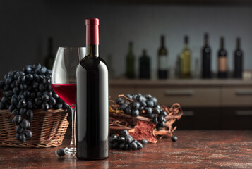 Bottle and glass of red wine with grapes on a vintage table.