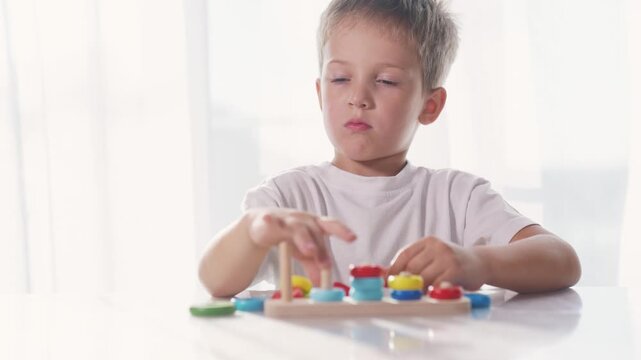 Boy is playing with toys to develop his motor skills. Learn color nursery concept. Child is playing with rings. Child is developing skills in developing motor skills with a ring of lifestyle toys.