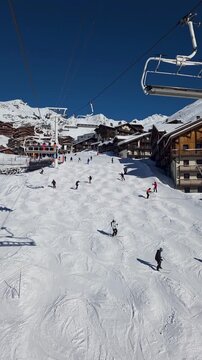 people skiing on slope at Val Thorens, 3 Valleys ski resort in French Alps. view from chairlift