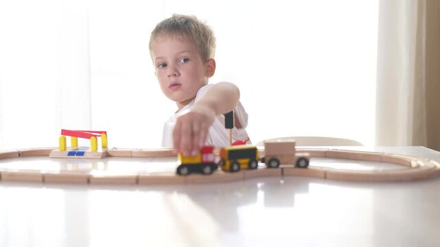 Boy plays with toy train indoors. childhood journey child concept. a boy plays on the railroad lifestyle in. kindergarten. a boy plays with a train on the railroad near a road.