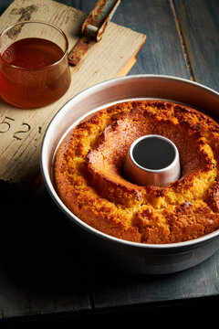 A round cake on a blue wooden table with a small bowl of honey