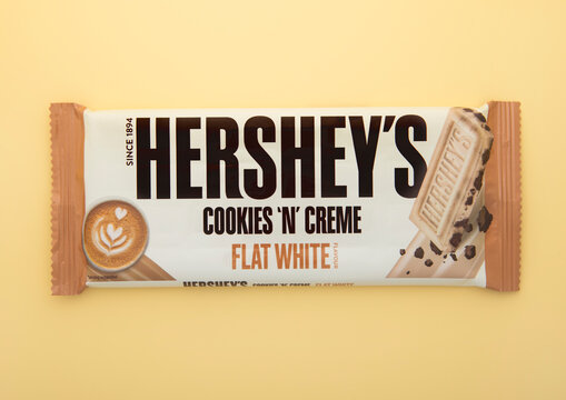 LONDON, UK - JANUARY 25, 2025: Hershey's cookies and creme chocolate with flat white flavor bar on light golden yellow background.