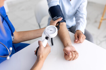 Blood pressure measurement. Close up of nurse hands using sphygmomanometer on patient arm in clinic. Healthcare and medicine concept, medical professional checking hypertension for senior woman.