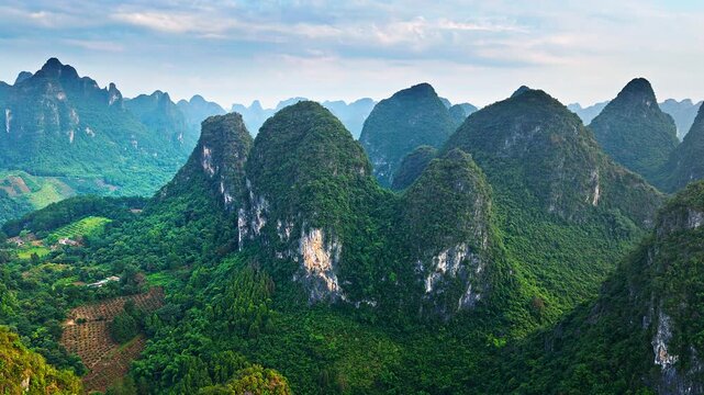 Aerial view of magnificent karst mountains covered with lush green vegetation under a cloudy sky in Guilin, China.