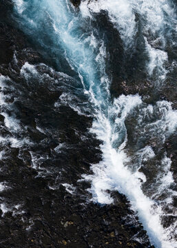 Aerial view of glacial river's turquoise veins carving through the dark, rugged terrain, a dance of raw power and serene beauty, Selfoss, Iceland.