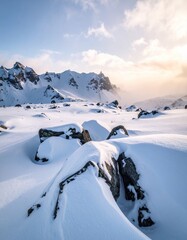 Snowy mountain scene with boulders and cloudy skies