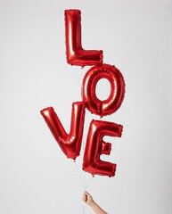 hand holding stacked red foil balloons spelling love against a plain white background for valentine's day or anniversary celebration