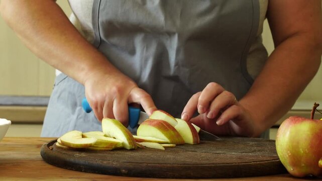 Woman cuts apples and pears for pie
