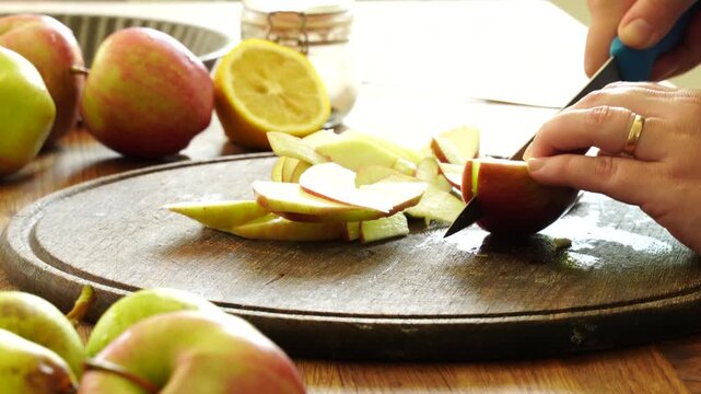 Woman cuts apples and pears for pie
