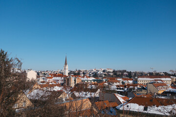 Obraz premium Panoramic view of a European city skyline with snow-covered rooftops under a clear blue sky