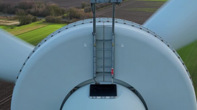 Detailed drone perspective of wind turbine mechanical components and nose cone in a rural landscape