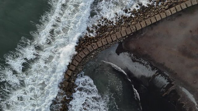 Aerial Drone View of Waves Crashing on a Curved Breakwater in Porto Pino, Sardinia, Italy