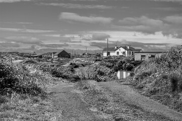 A black and white photo of a rural area with a dirt road and a house