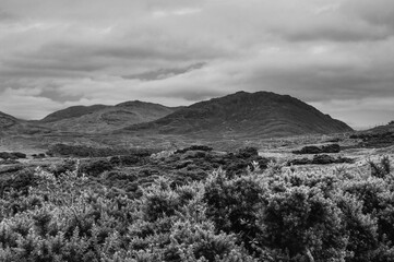 A black and white photo of a mountain range with a cloudy sky