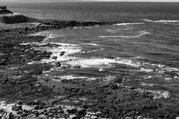 A black and white photo of a rocky shoreline with the ocean in the background