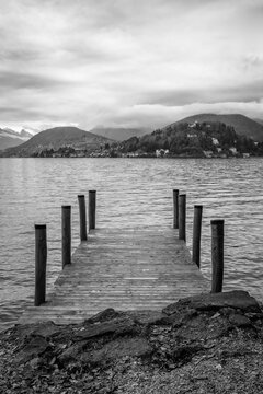 Wooden jetty along the winter water of Orta Lake (piedmont, Northern Italy) with the alps in the background. UNESCO World Heritage Site, its San Giulio island is home to a convent of cloistered nuns.