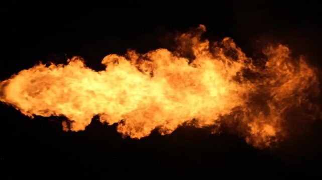 Energetic bright orange flame jet blasting from left on black background, abstract energy.