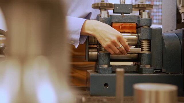 Jeweler processing silver through professional rolling mill.
