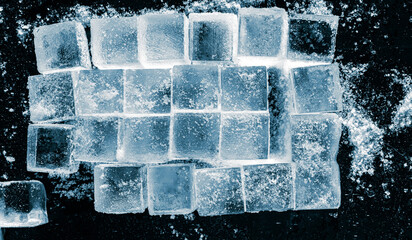 Ice cubes, arranged in a rows on black background.