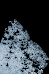 Ice texture on a black background. Frozen texture. Textured cold frosty surface of the ice on a black background.