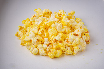 Obraz premium A delightful mound of fluffy popcorn rests on a white surface, perfect for sharing during film time