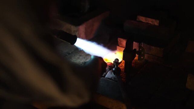 Professional jeweler melting precious metal with gas torch.