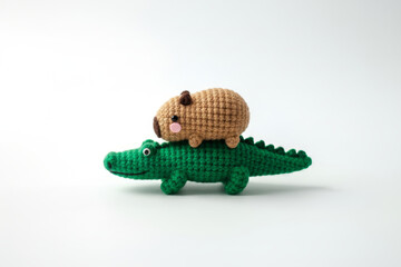 Obraz premium Crochet amigurumi capybara riding green crocodile handmade yarn toys. Creative friendship concept for kids decor nursery branding toy store advertisements animal cafe mascot cute hobby craft design