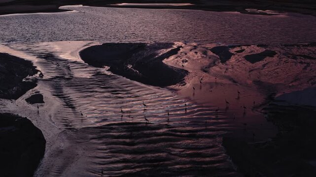 Industrial sand dredging and water channels at Luanda Bay, Angola, during sunset with birds