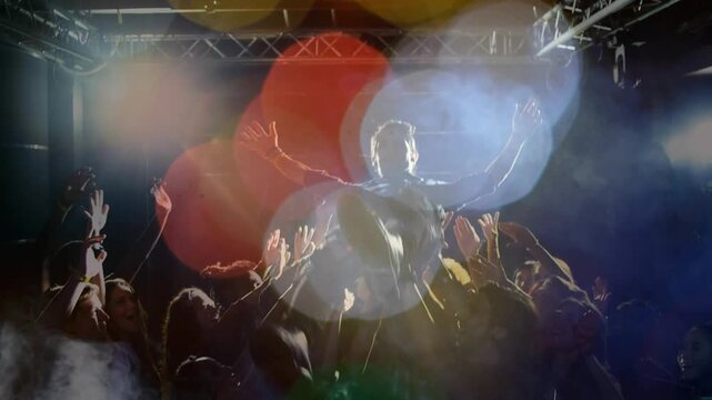 Performer raising arms, rallying concertgoers, launching stage dive, crowdsurfing under lights haze